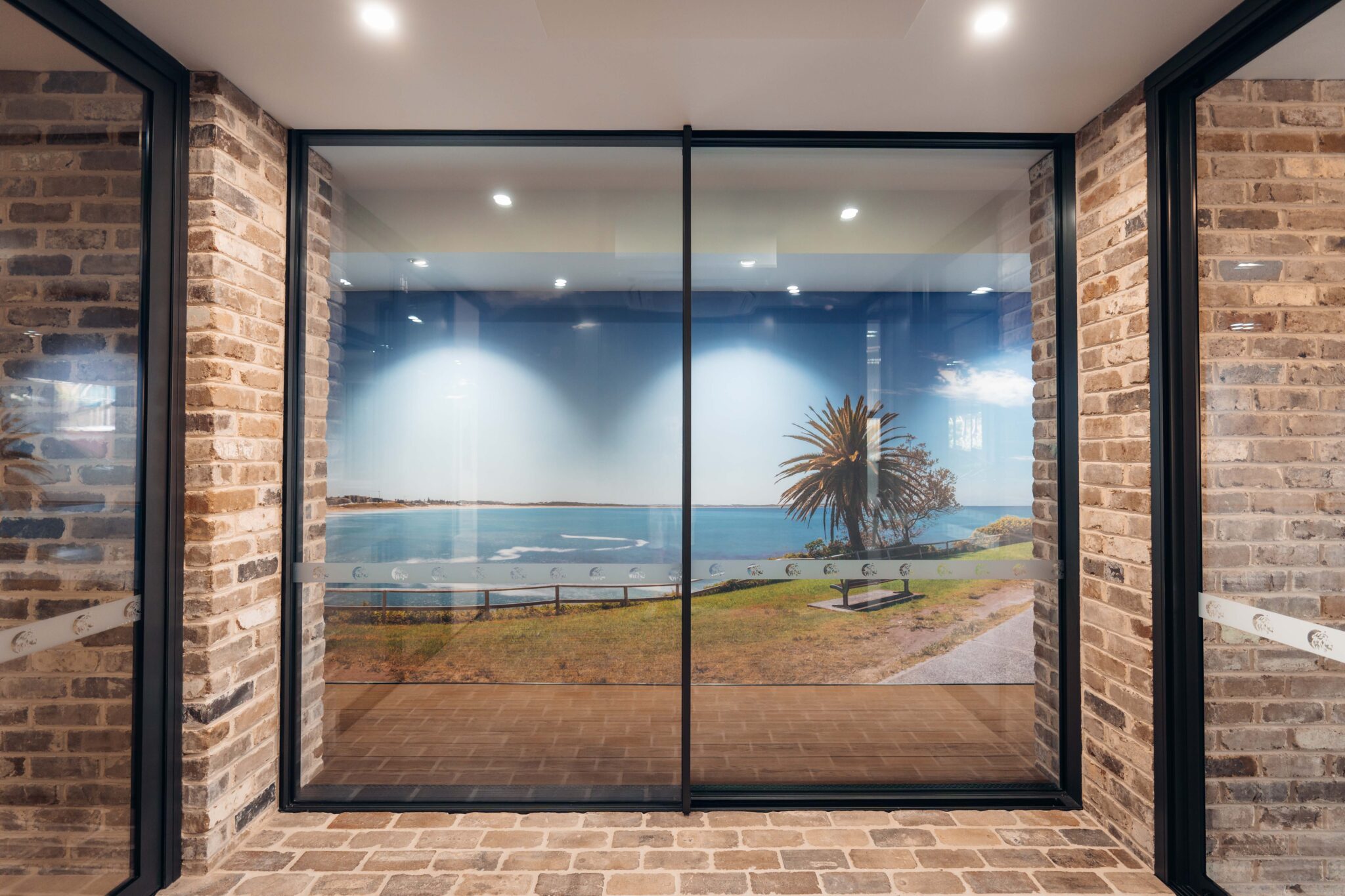 Coastal mural in rustic brick hallway with beach view and palm tree.